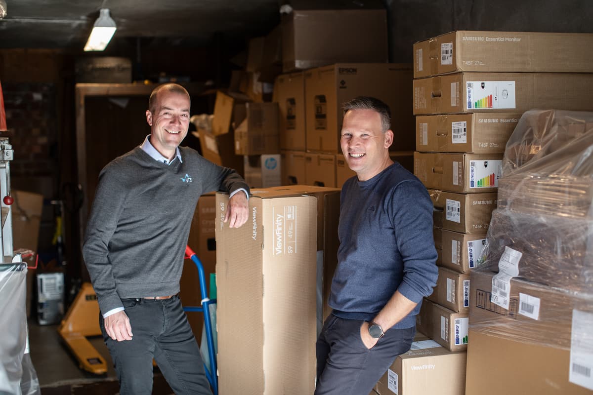 Morten Resve og Tore Forbord på lageret To smilende menn på et rom med mange pappesker
