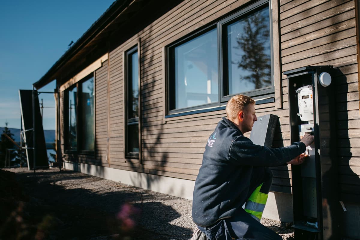 vegar sikringsskap Elektriker jobber i et sikringsskap som står på en hyttevegg