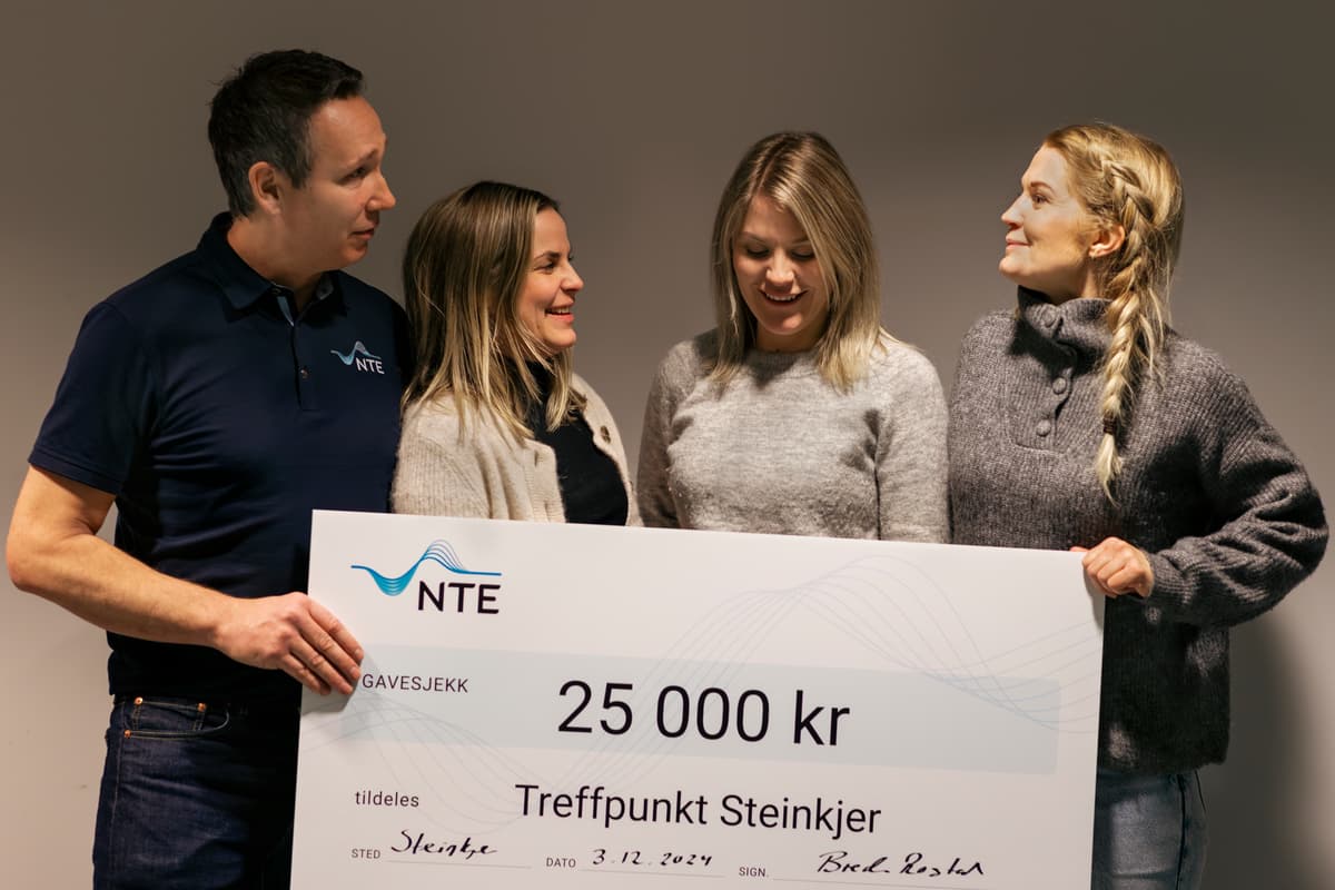 Brede og damene En mann og tre damer holder leende opp en sjekk på 25 000 kroner.