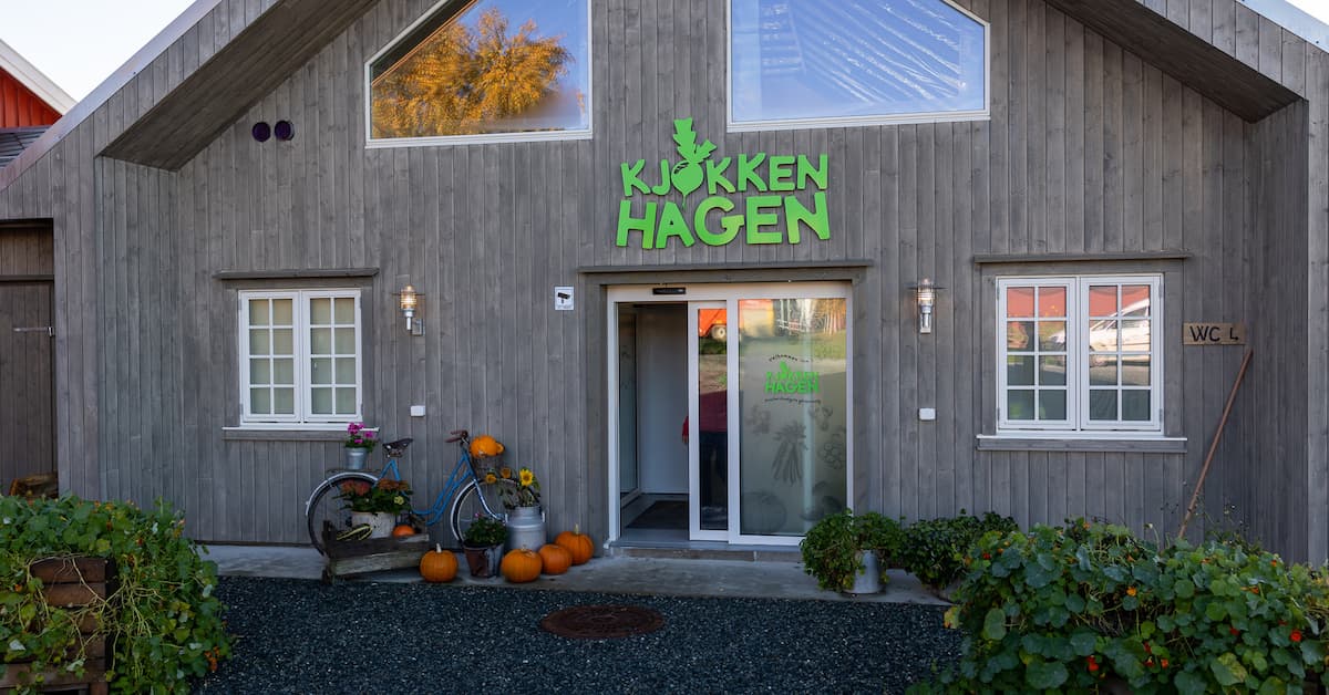 inngangsparti kjøkkenhagen Inngangsparti til et hus hvor det står en sykkel og et melkespann med gresskar utenfor