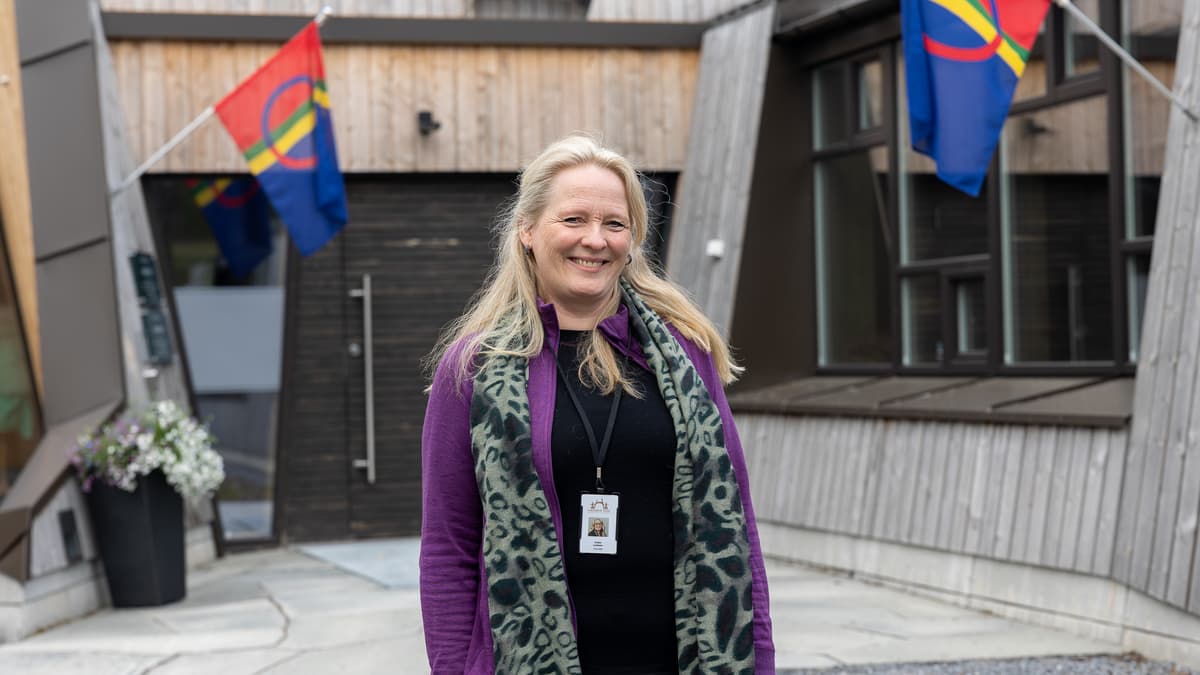 Snåsa portrett av dame Smilende dame foran et inngangsparti flankert av to samiske flagg