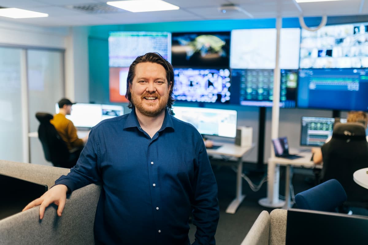 arild hembre Similende mann foran en vegg dekket av store skjermer