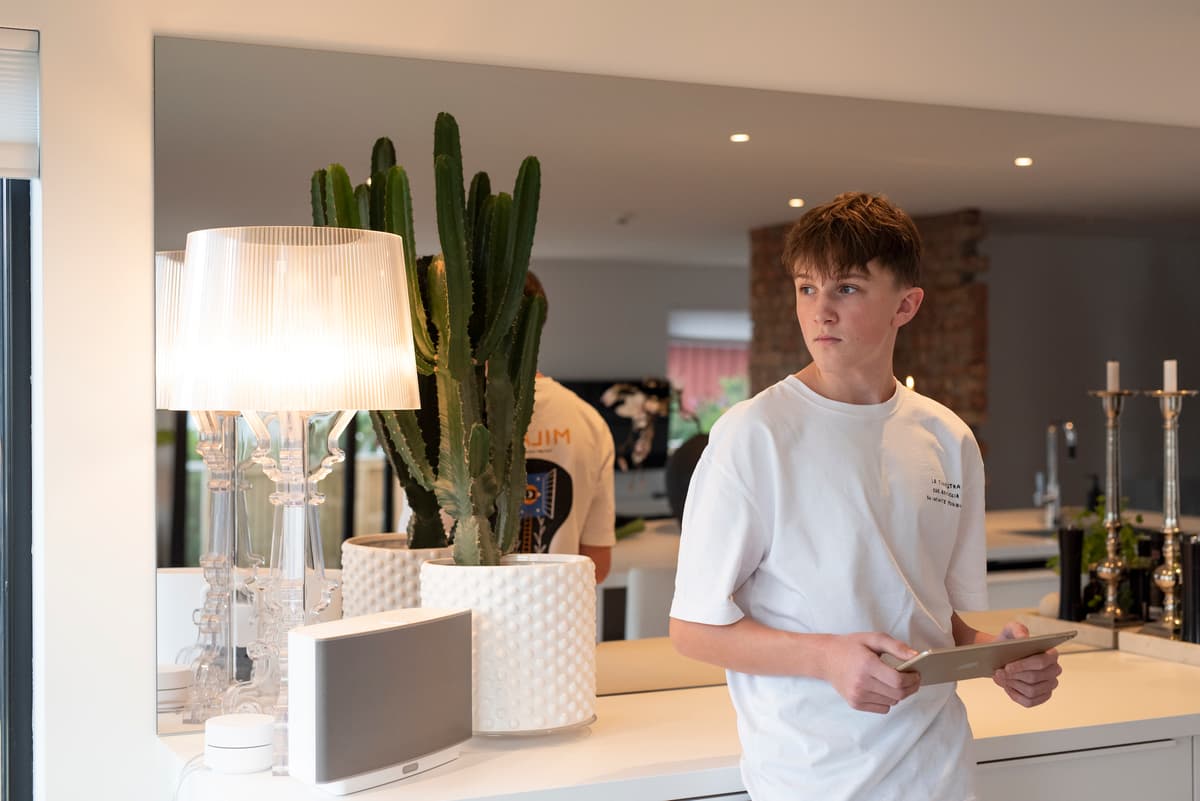 Gutt med iPad2 Tenåringsgutt holder en iPad mens han lener seg mot en kjøkkenbenk