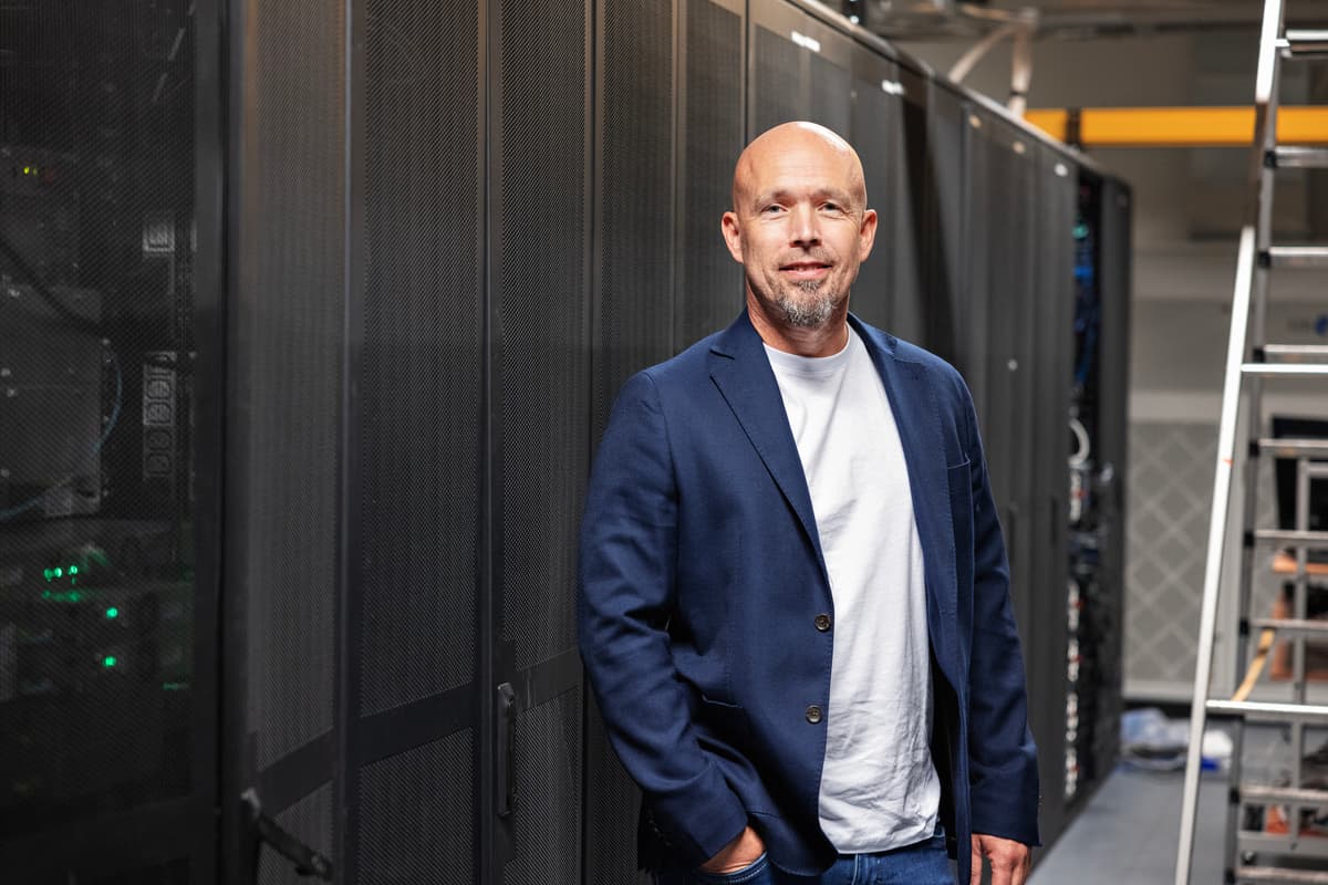 Smilende mann i dressjakke foran en lang rekke med skap Smilende mann i dressjakke foran en lang rekke med skap