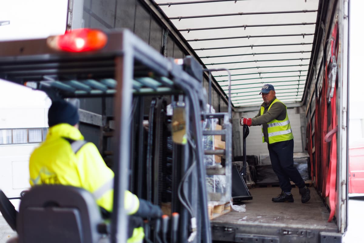 dimitri En mann laster paller inn i en lastebil med gaffeltruck mens en annen mann tar imot pallene