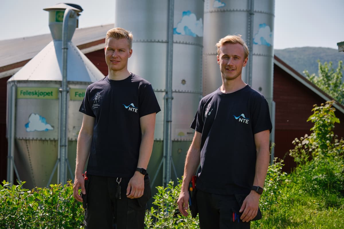 elektrikerne To blide mannlige elektrikere foran siloer