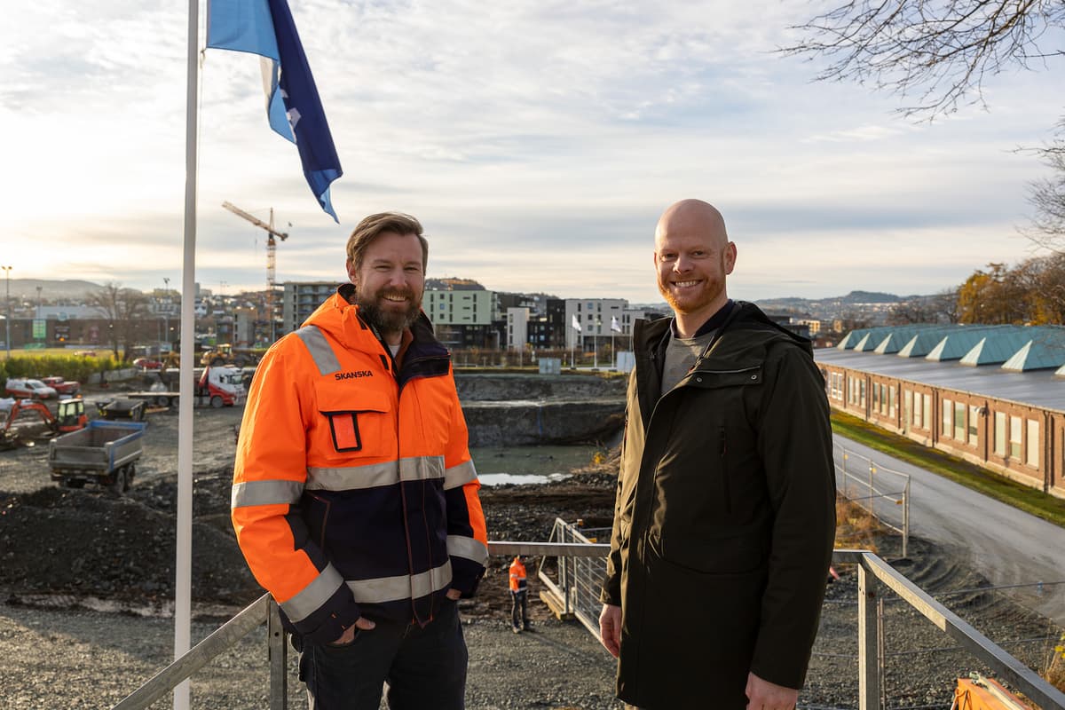 To smilende menn foran en byggeplass To smilende menn foran en byggeplass