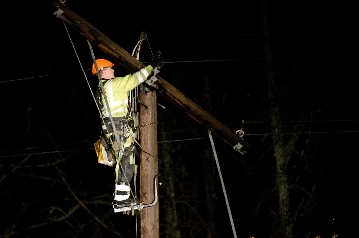 Montør øverst på strømmast reparerer strømledningen Montør øverst på strømmast reparerer strømledningen