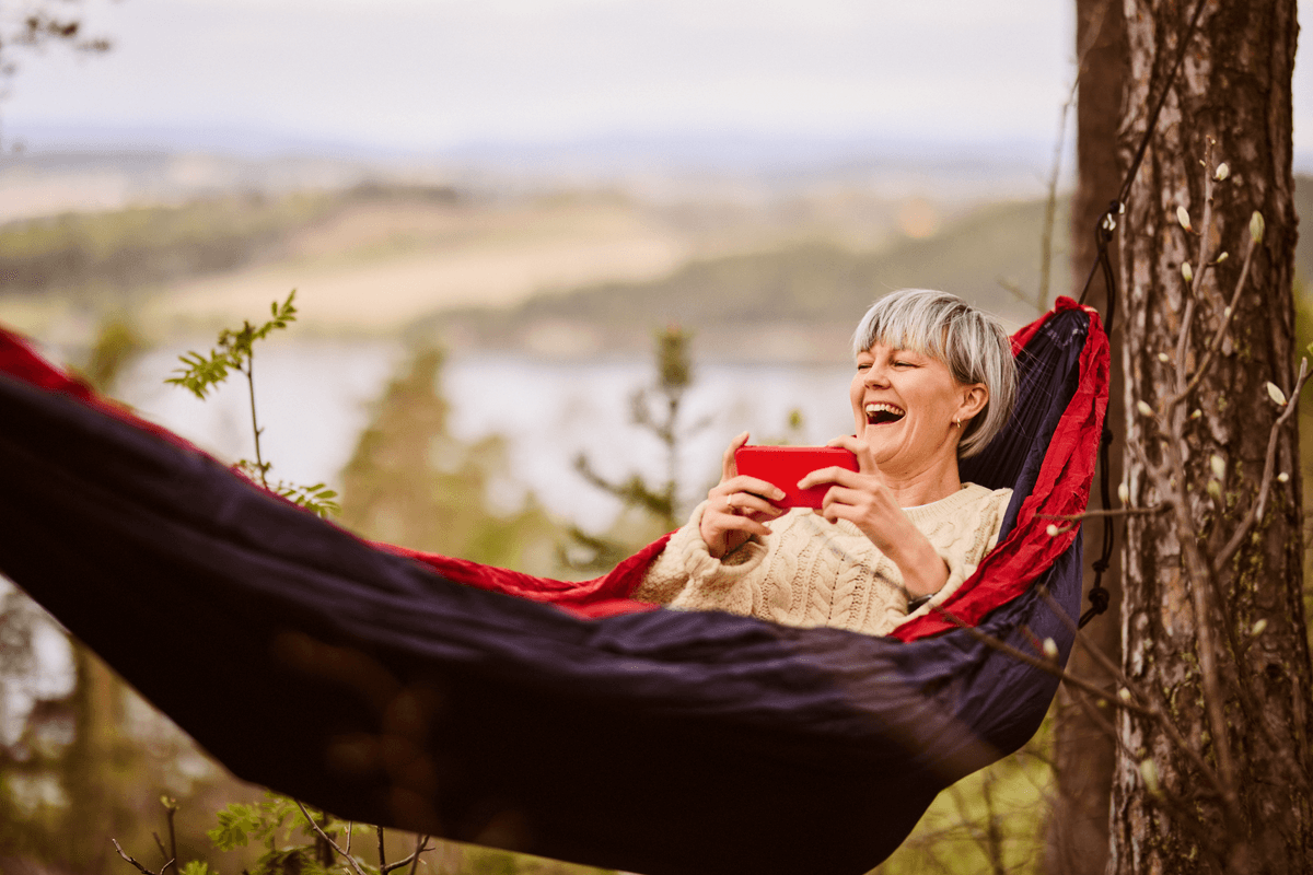 Ta med Altibox-appen på tur. Foto: Andreas Kleiberg, Altibox Kvinne i hengekøye ser på mobilen
