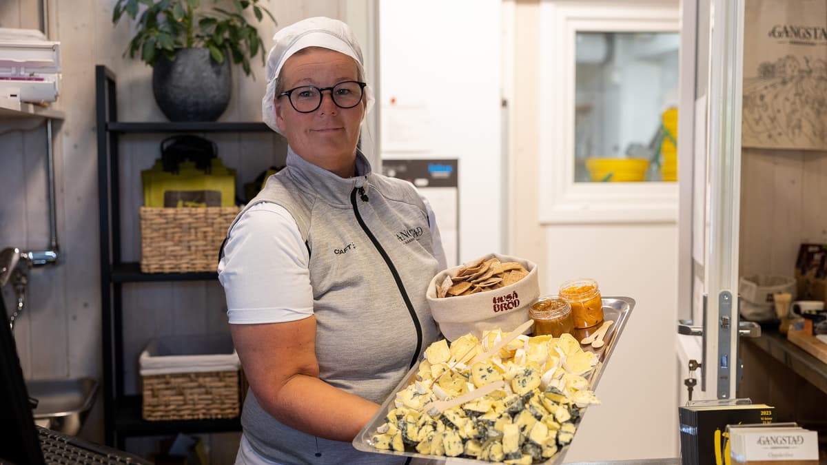 Gangstad ost og dame Dame holder et fat med ost, kjeks og marmelade