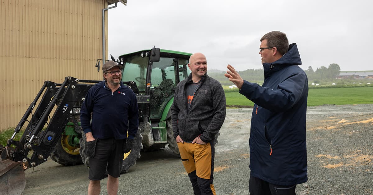 Tre smilende menn i samtale foran en traktor Tre smilende menn i samtale foran en traktor