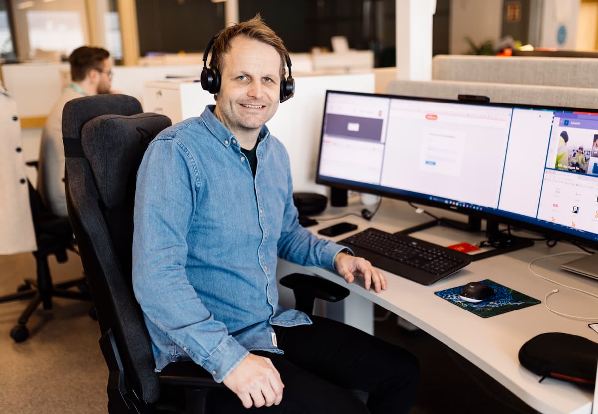 petter heggum Smilende mann med hodetelefoner sitter ved e pult med to store dataskjermer