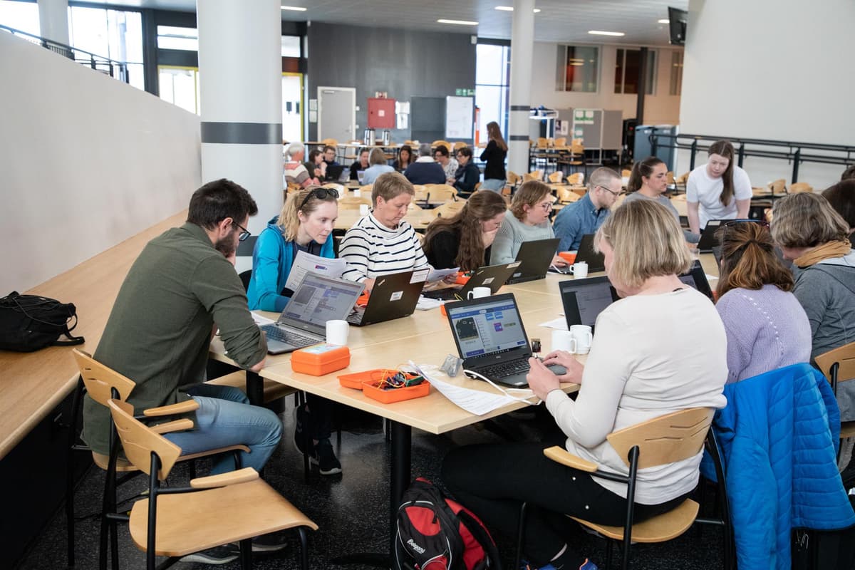 Lærer ved en skole sitter i lag å lære om koding for kids Lærer ved en skole sitter i lag å lære om koding for kids