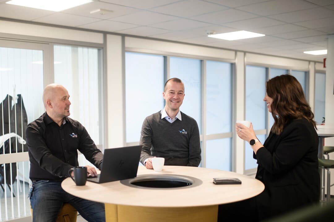 Bilde av to menn og en dame som sitter rundt et bord i en uformell samtale. Bilde av to menn og en dame som sitter rundt et bord i en uformell samtale.