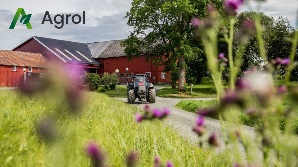 Agrol Logo Traktor En traktor foran et rødt gårdsbygg med logoen til "Agrol"