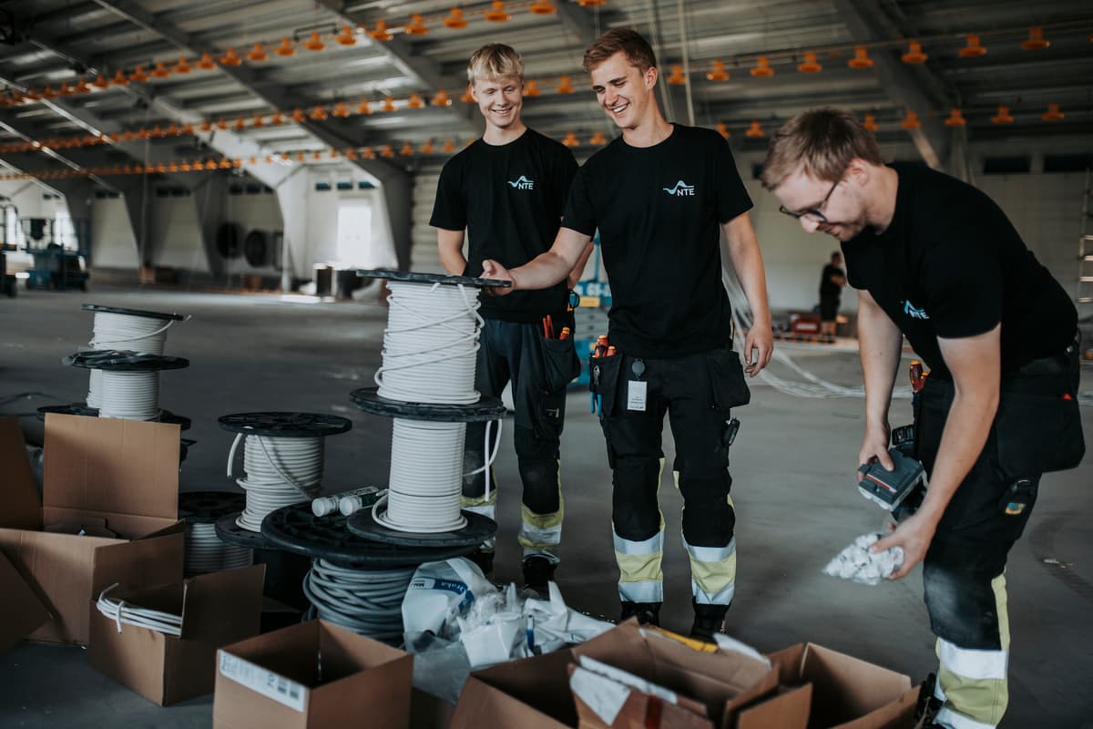 elektrikere i kyllingfjøs 3 mannlige elektrikere foran pappesker med utstyr